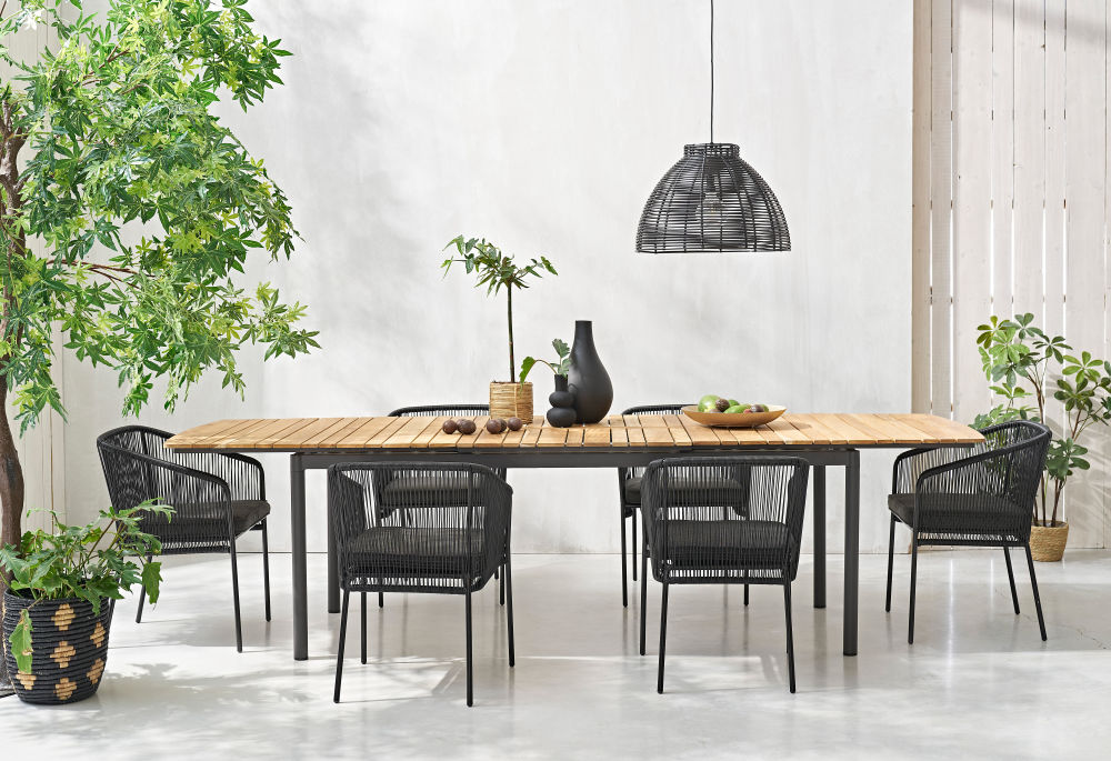 Table de jardin extensible Guam en bois de teck massif et aluminium gris anthracite, ambiance extérieure avec décoration – Dakar, Sénégal.