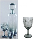 Ensemble de verrerie grise comprenant une carafe avec bouchon sphérique, une coupe à pied Visage et un verre assorti, sur une table à Dakar, Sénégal.