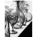 Gros plan artistique en noir et blanc d'une coupe à pied Visage en verre gris, entourée de carafes et autres verreries sur une étagère, à Dakar, Sénégal.
