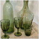 Ensemble de verres à pied et carafes en verre vert, mettant en valeur des motifs de visage. Dakar, Sénégal.