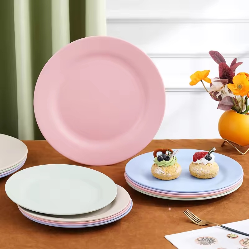 Collection de dessous d'assiettes colorés en céramique avec une assiette rose mise en avant et des pâtisseries sur une table élégante - Dakar, Sénégal